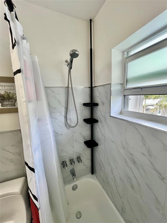 bathroom with shower / tub combo and toilet