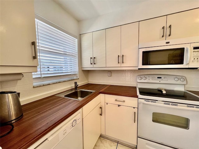 kitchen with wood counters, white appliances, sink, light tile patterned floors, and white cabinetry