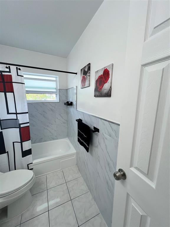 bathroom with tile patterned floors, shower / bath combo, toilet, and tile walls