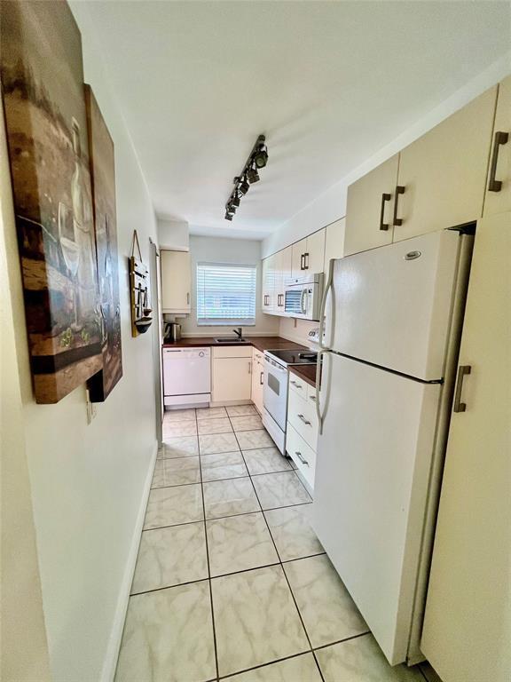 kitchen featuring white cabinets, white appliances, sink, and track lighting