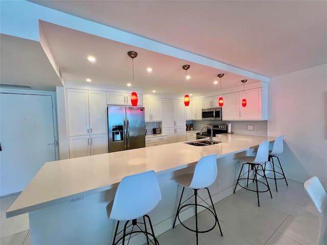 kitchen with kitchen peninsula, sink, decorative light fixtures, and appliances with stainless steel finishes