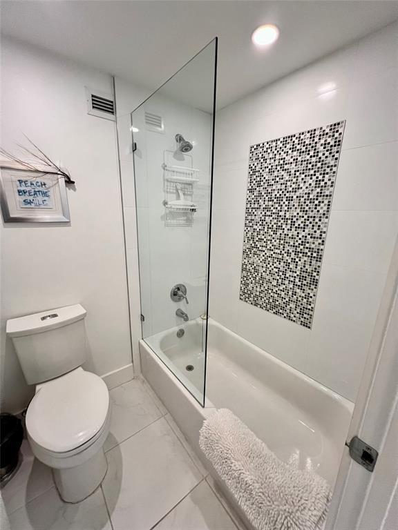 bathroom featuring toilet and tiled shower / bath