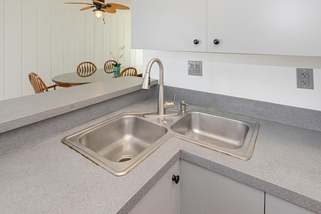 room details with white cabinets, ceiling fan, and sink