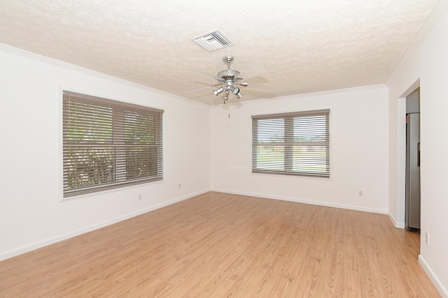 empty room with ceiling fan, light hardwood / wood-style floors, ornamental molding, and a textured ceiling