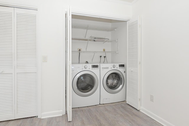 clothes washing area with independent washer and dryer and light hardwood / wood-style flooring