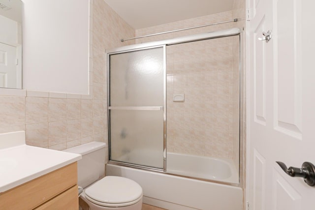 full bathroom with vanity, shower / bath combination with glass door, toilet, tile walls, and tasteful backsplash