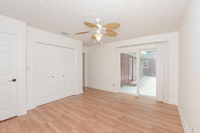 unfurnished bedroom with ceiling fan, light hardwood / wood-style floors, a textured ceiling, access to outside, and a closet