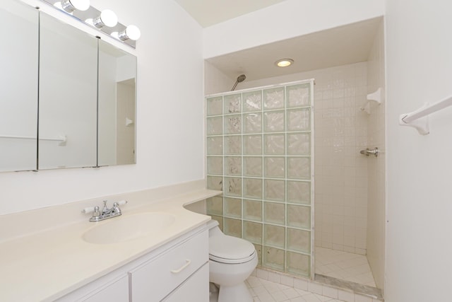 bathroom with tiled shower, vanity, toilet, and tile patterned flooring