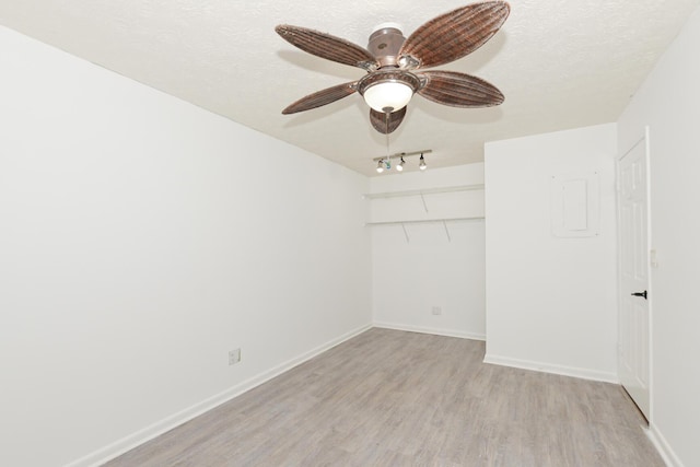 empty room featuring ceiling fan, light hardwood / wood-style flooring, track lighting, and a textured ceiling