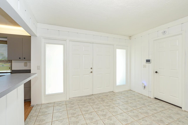 foyer featuring light tile patterned floors, a textured ceiling, and a wealth of natural light