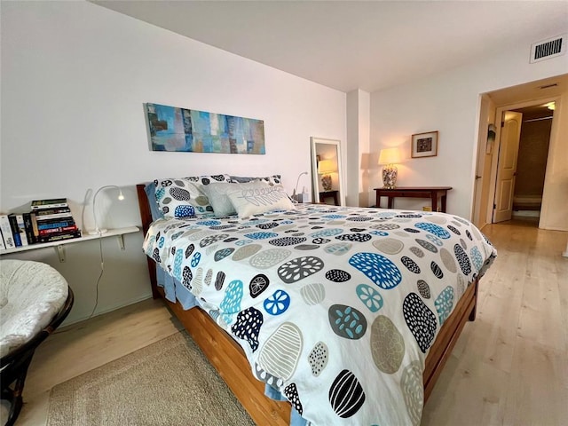 bedroom with connected bathroom and light hardwood / wood-style flooring