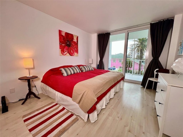 bedroom featuring expansive windows, access to exterior, and light hardwood / wood-style flooring