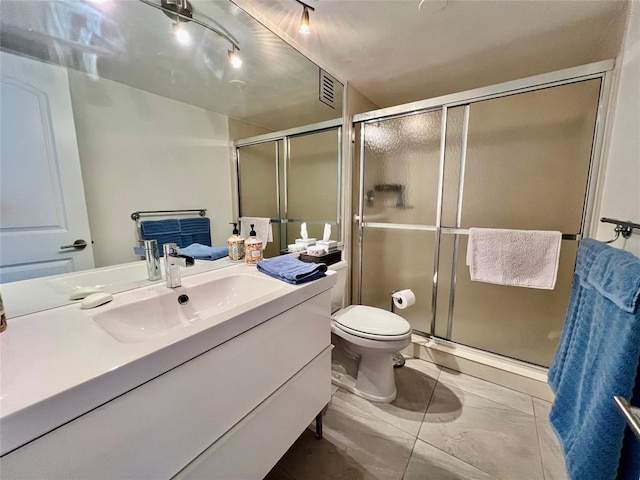 bathroom featuring vanity, toilet, and a shower with door