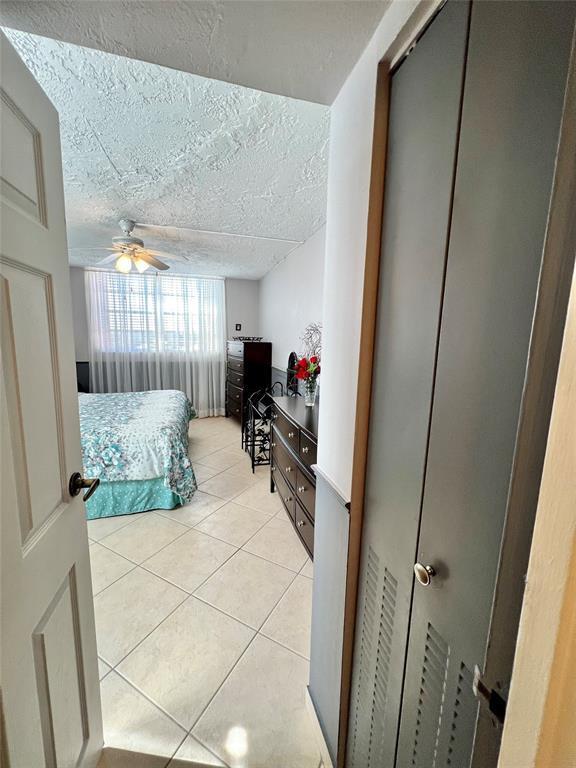 tiled bedroom with a textured ceiling and ceiling fan