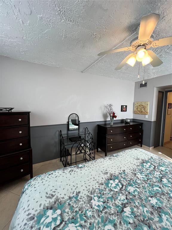 tiled bedroom featuring ceiling fan and a textured ceiling