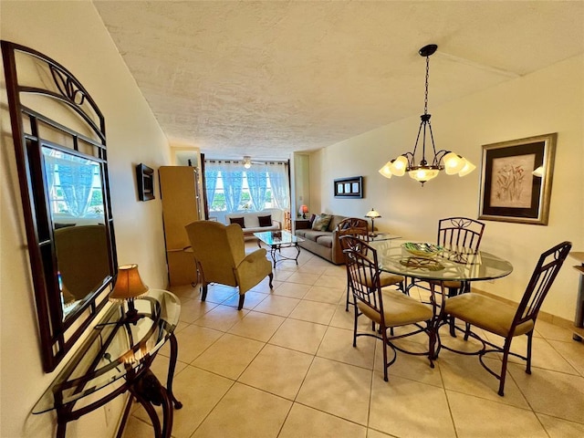 tiled dining space featuring ceiling fan with notable chandelier and a textured ceiling