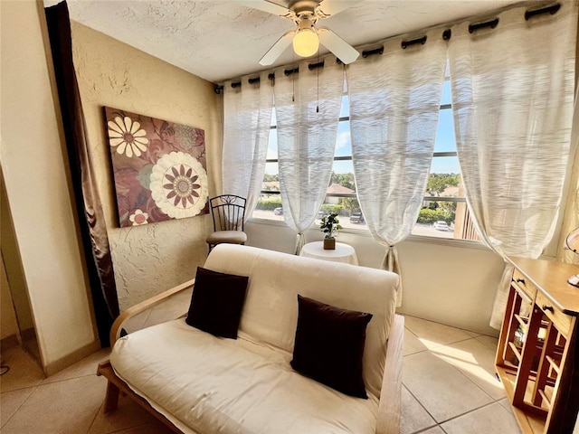 sitting room with ceiling fan, light tile patterned floors, and a textured ceiling