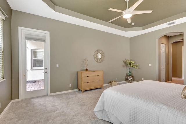 carpeted bedroom featuring ceiling fan and a tray ceiling