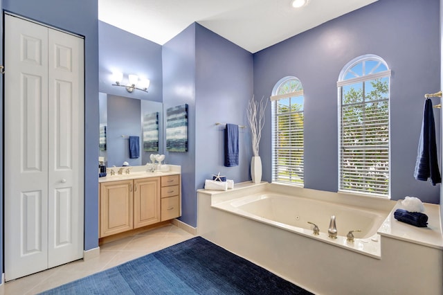 bathroom with tile patterned flooring, a tub to relax in, and vanity