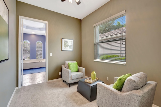 living area with light carpet and ceiling fan