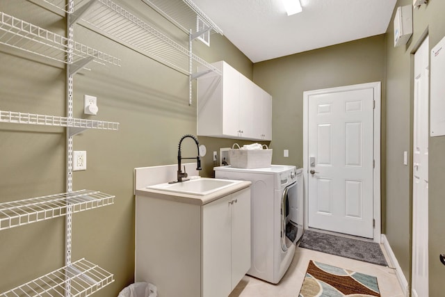 laundry area featuring washer and clothes dryer, sink, light tile patterned floors, and cabinets