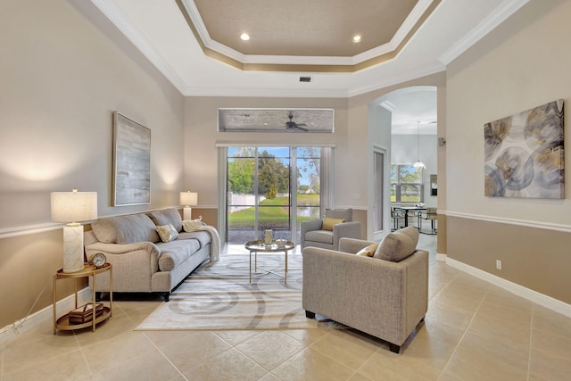 living room featuring ceiling fan, light tile patterned floors, crown molding, and a tray ceiling