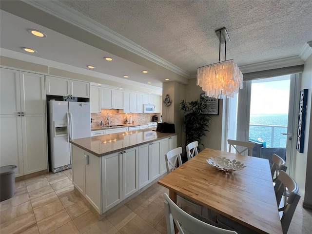 kitchen with white appliances, white cabinets, sink, hanging light fixtures, and a textured ceiling