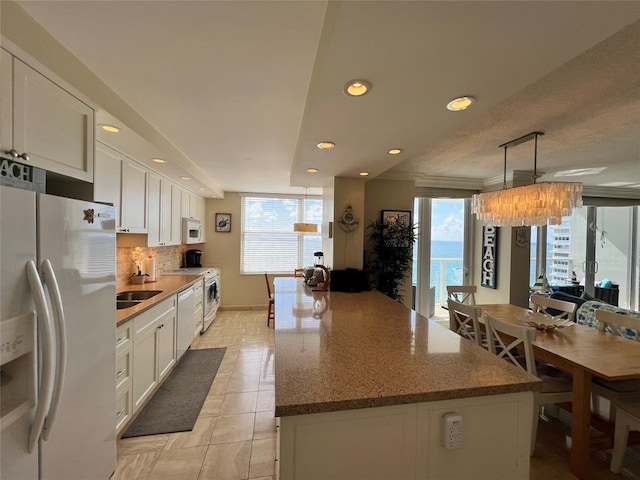 kitchen with white cabinets, white appliances, decorative light fixtures, and a water view