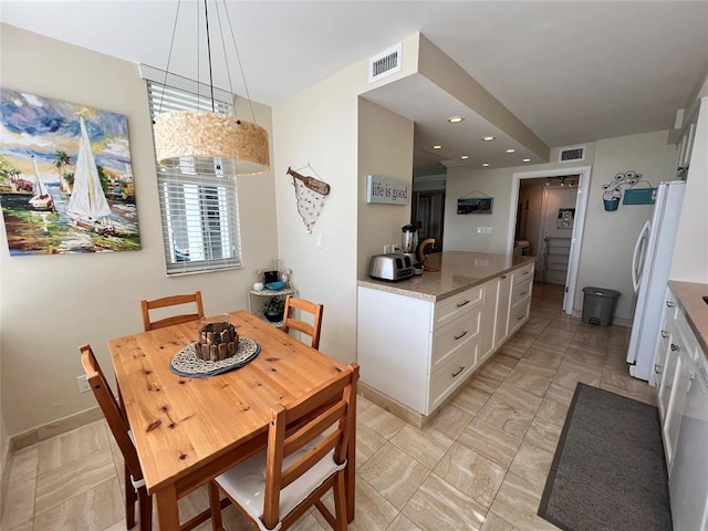 kitchen featuring light stone countertops, white cabinets, pendant lighting, and white refrigerator