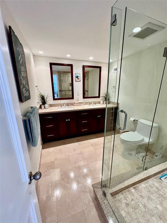 bathroom featuring vanity, toilet, and a shower with shower door