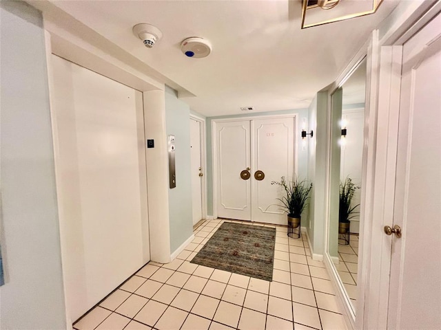 corridor with light tile patterned floors and elevator