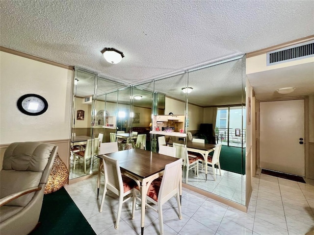 tiled dining room featuring a textured ceiling and ornamental molding