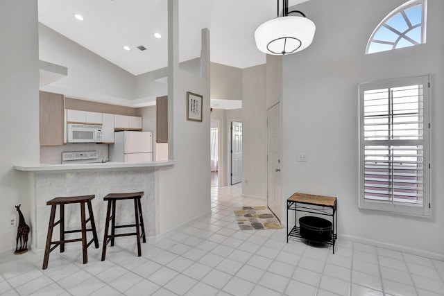 kitchen featuring high vaulted ceiling, tasteful backsplash, light tile patterned floors, kitchen peninsula, and white appliances