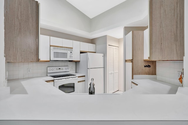 kitchen with tasteful backsplash, white cabinetry, and white appliances