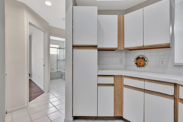 kitchen featuring white cabinetry, light tile patterned floors, and backsplash