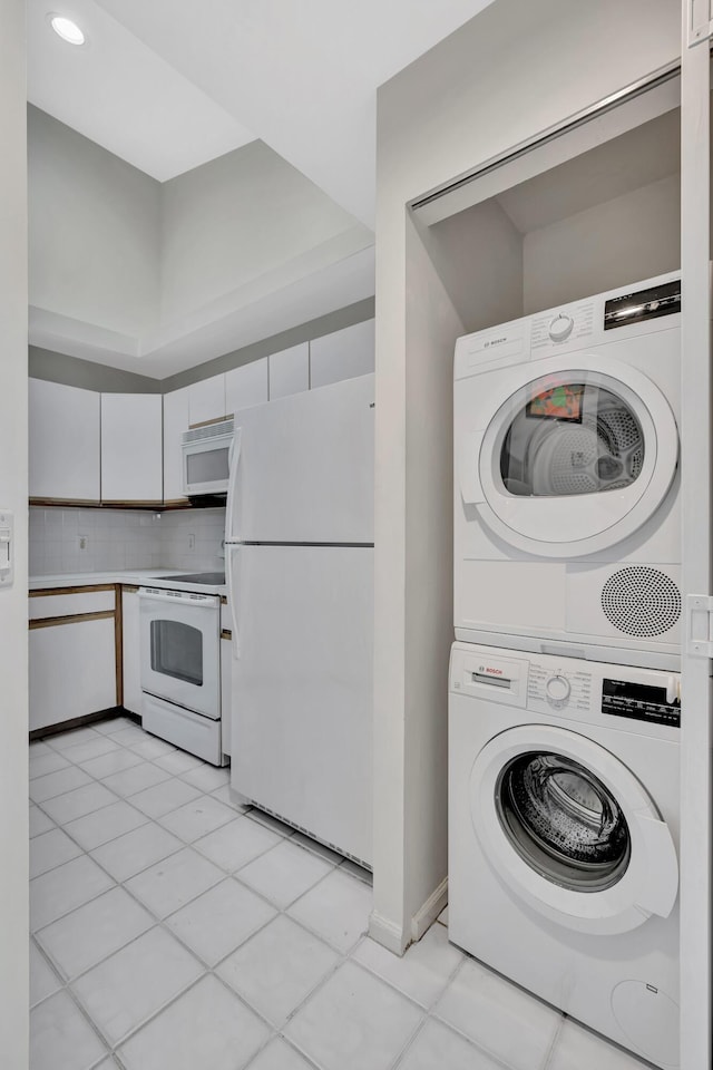 laundry area with stacked washer / dryer and light tile patterned floors