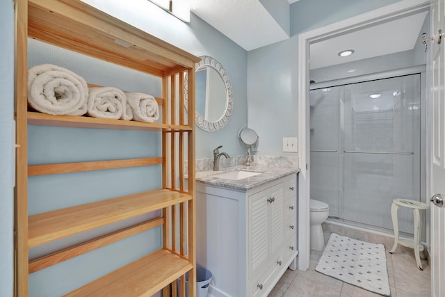 bathroom featuring tile patterned flooring, toilet, a shower stall, and vanity