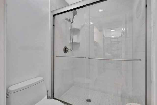 bathroom featuring toilet and a shower with shower door