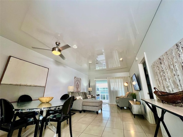 dining room with ceiling fan, light tile patterned flooring, and a high ceiling