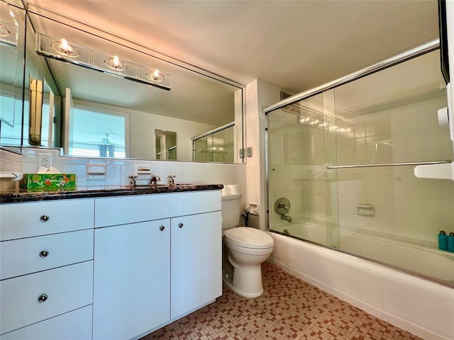 full bathroom featuring backsplash, vanity, toilet, and bath / shower combo with glass door