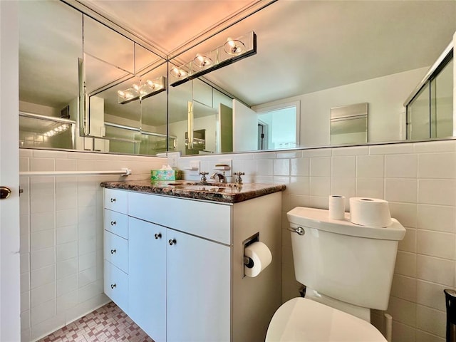 bathroom featuring vanity, toilet, a shower with door, and tile walls