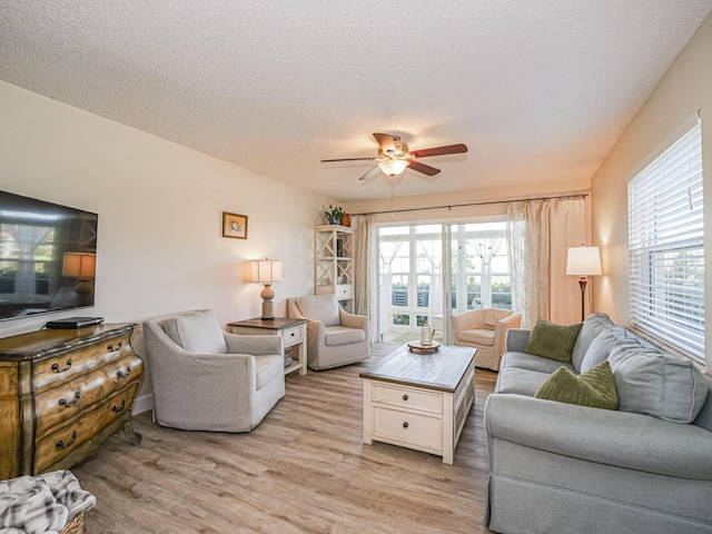 living room with ceiling fan, light hardwood / wood-style flooring, and a textured ceiling