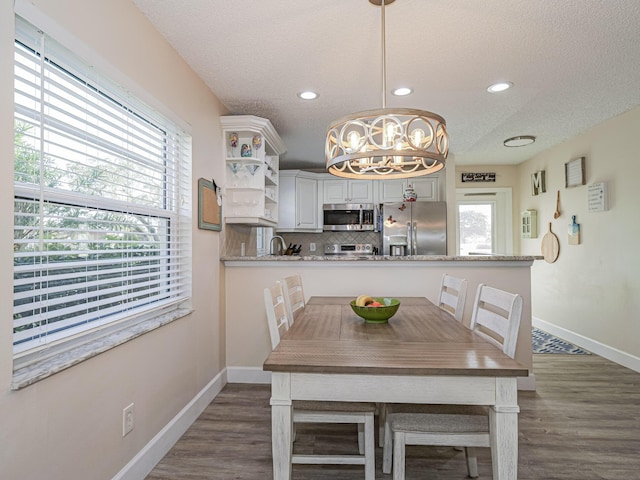 dining area with a chandelier, a wealth of natural light, and dark wood-type flooring