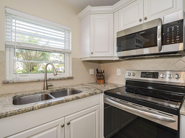 kitchen with white cabinets, appliances with stainless steel finishes, decorative backsplash, and sink