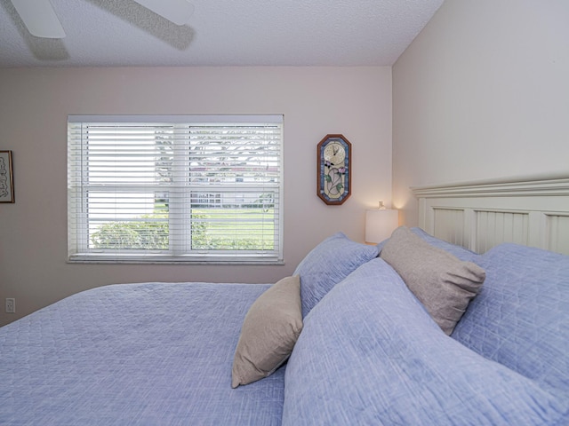 bedroom with multiple windows, ceiling fan, and a textured ceiling