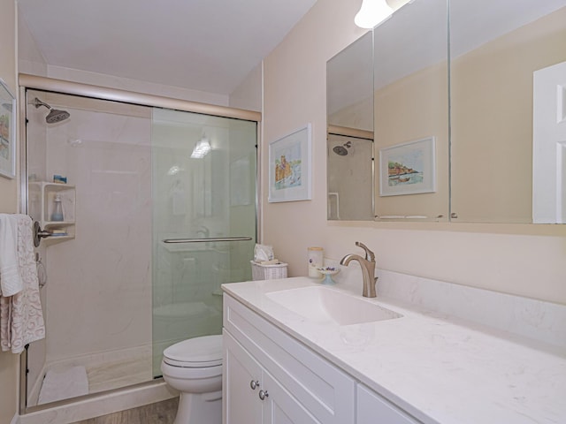 bathroom with hardwood / wood-style floors, vanity, an enclosed shower, and toilet