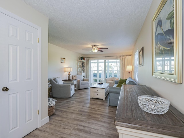 bedroom with hardwood / wood-style floors, ceiling fan, and a textured ceiling