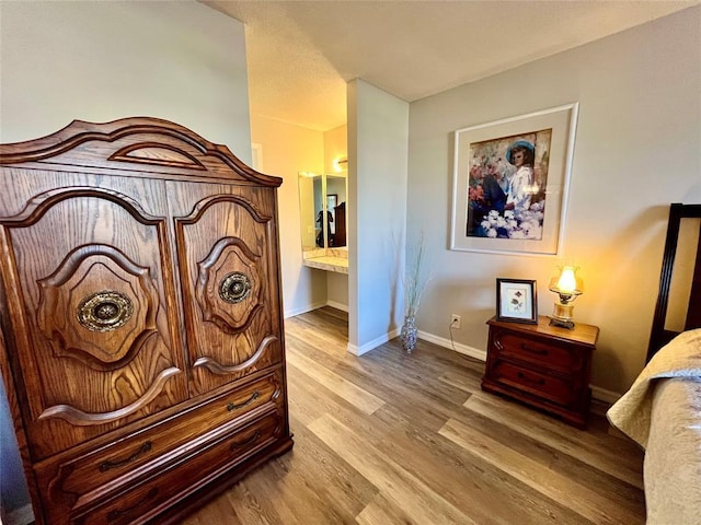 bedroom featuring light wood-type flooring and ensuite bath