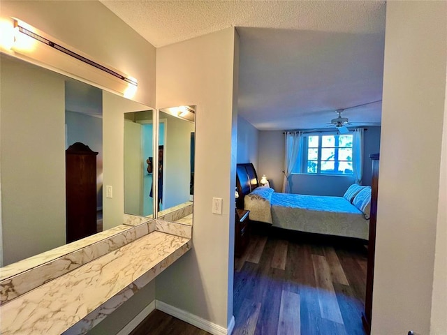 bedroom with a textured ceiling, ceiling fan, and dark wood-type flooring