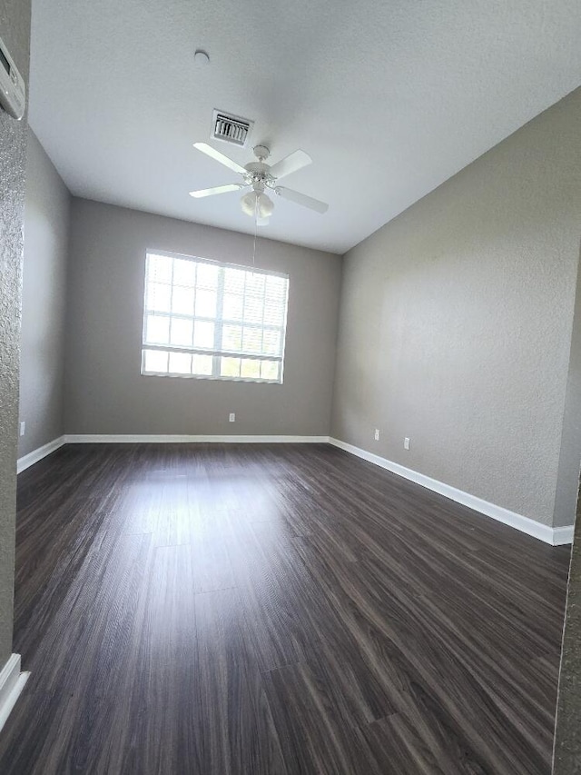 unfurnished room with a textured ceiling, ceiling fan, and dark wood-type flooring